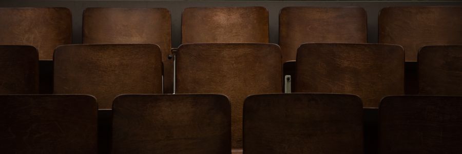 three rows of wooden theatre seats unfilled