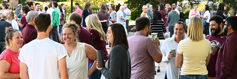 UM employees standing outside in various groups drinking coffee and chatting