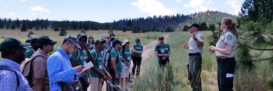 group of people on a trail listening to a presentation from US Forest Service employees