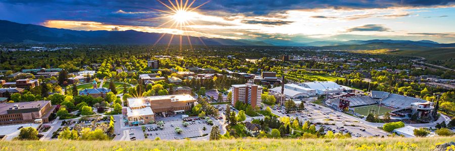 UM campus and Missoula from a hill with sun dramatically shining through the clouds