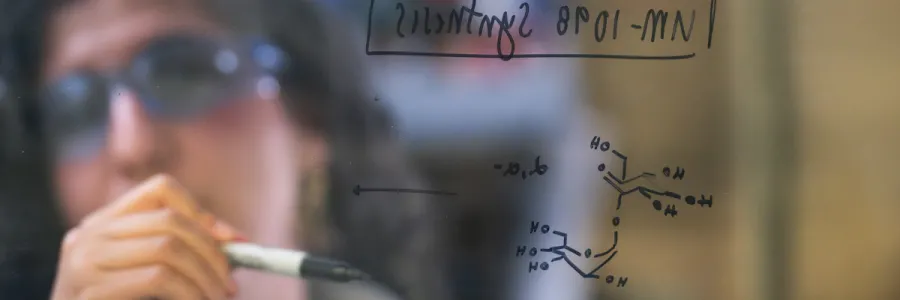 A ؿ researcher with UM’s Center for Translational Medicine studies a formula written on a window.