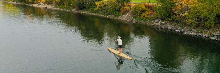 person on a stand up paddle board paddling down the Clark Fork River in Missoula