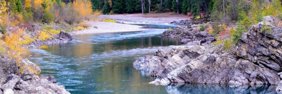 river winding through rocky banks with autumn colored trees along them