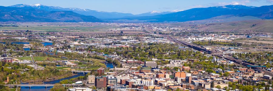 Missoula seen from above with downtown in the foreground and snowy mountains in the distance