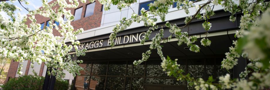 the skaggs building sign above the main entrance with flowering tree branches around it