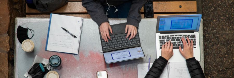 direct overhead view of two students typing on their laptops at a table 