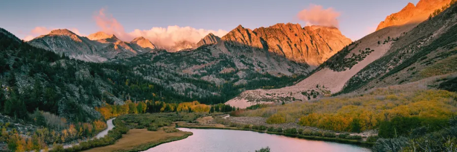 A stunning mountainous landscape with a tranquil river and vibrant autumn foliage.