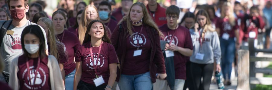 large group of students in griz colors walking along a path on the UM campus