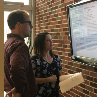 A faculty member and a student look at a text on a screen