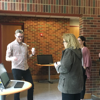 Faculty members gather around a student who is presenting