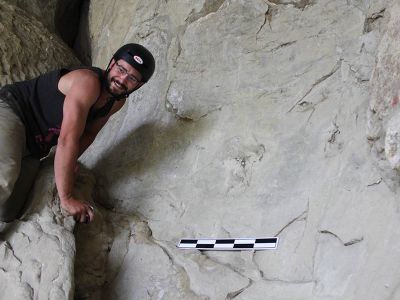 Student standing next to finding in stone