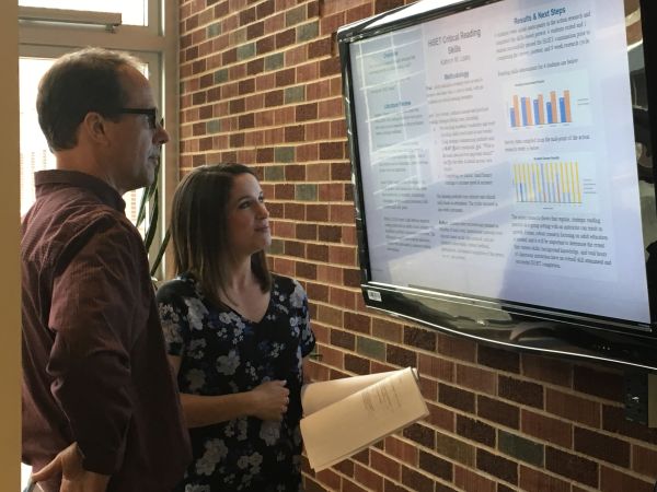 A faculty member and a student look at a text on a screen