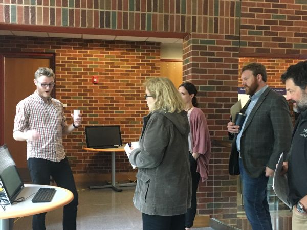 Faculty members gather around a student who is presenting