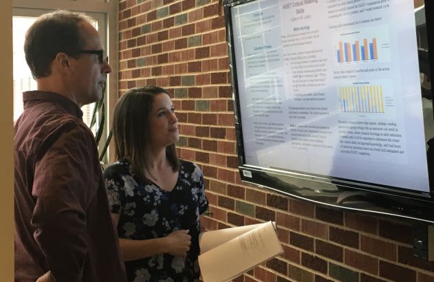 A faculty member and a student look at a text on a screen