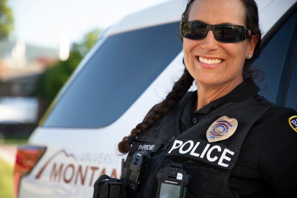 female UMPD officer smiling in front of police car
