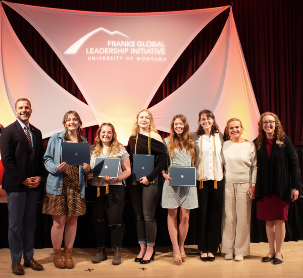 Group of students stand in front of a stage