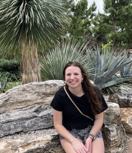 Dr. Amy Violante sitting outside on a rock smiling
