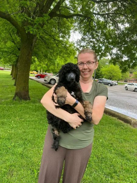 Deborah Ith standing outside in grass holding a dog