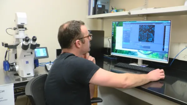 A researcher sits in front of a computer screen.