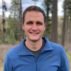 A person wearing a blue light sweater smirks at the camera.