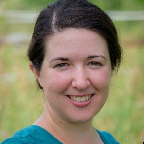 A person with pulled back brown hair smiles at the camera.