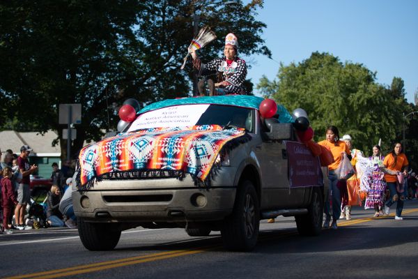 2022 Miss Kyiyo Riding on top of a truck, decorated with native blankets, as kyiyo club member toss candy out, during 2022 Homecoming parade
