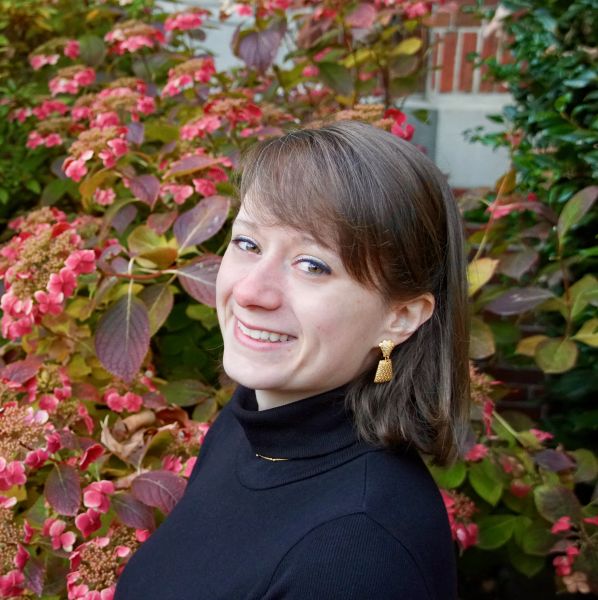 Polly Lauer headshot; Polly standing in-front of green and pink foliage