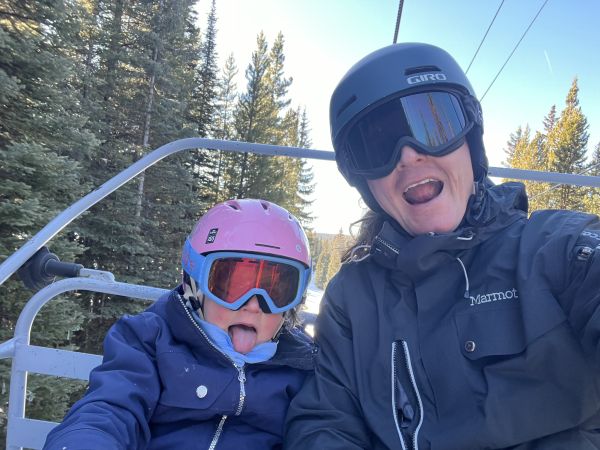 Patrick and his child on a chairlift in the winter time at a snow resort.