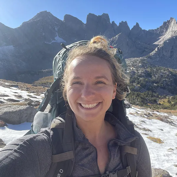 Ellie Hainsworth wears a backpack in the mountains