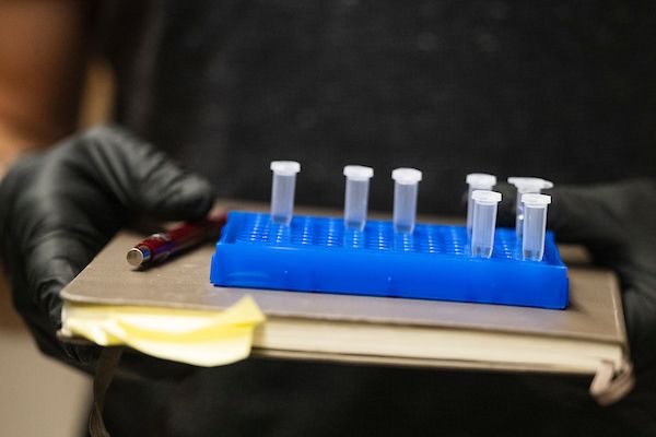 Student loads test tube with pipette in lab.