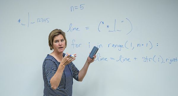 a UM computer science professor points to an equation on a white board