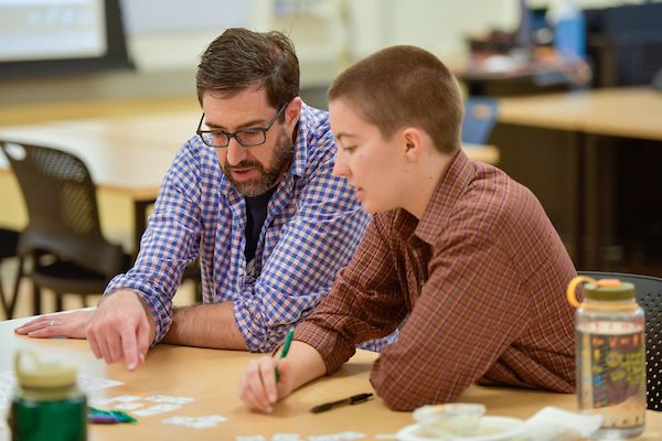 A UM professor teaches a student at a table