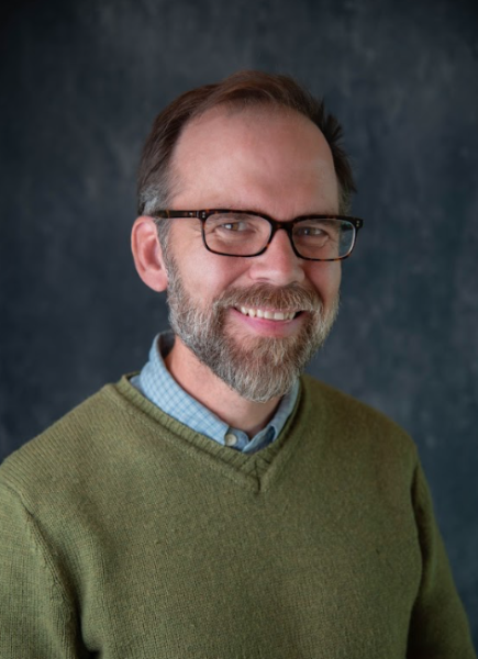 derek in a green button-up shirt smiling