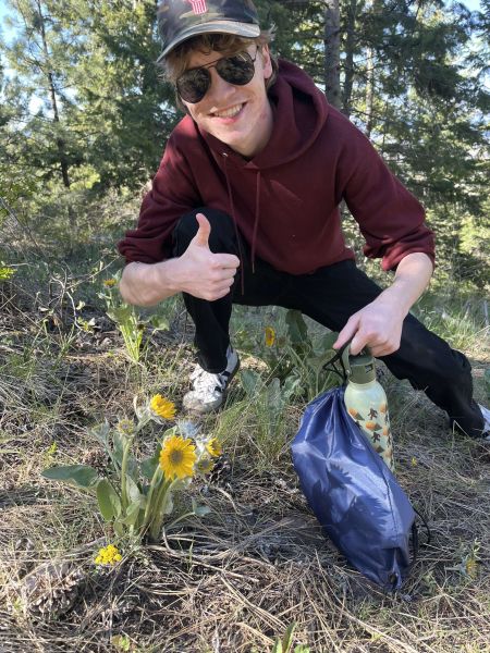 tristan in the woods pointing to a wild flower