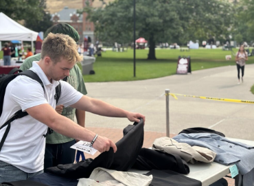 young man sifts through professional clothes during the career closet