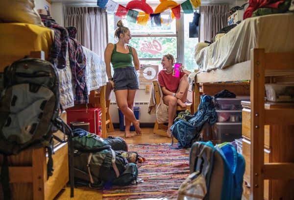 two girls smiling inside their newly-furnished dorm room
