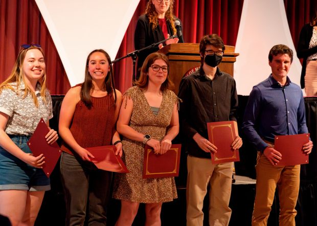 Group of students stand in front of a stage