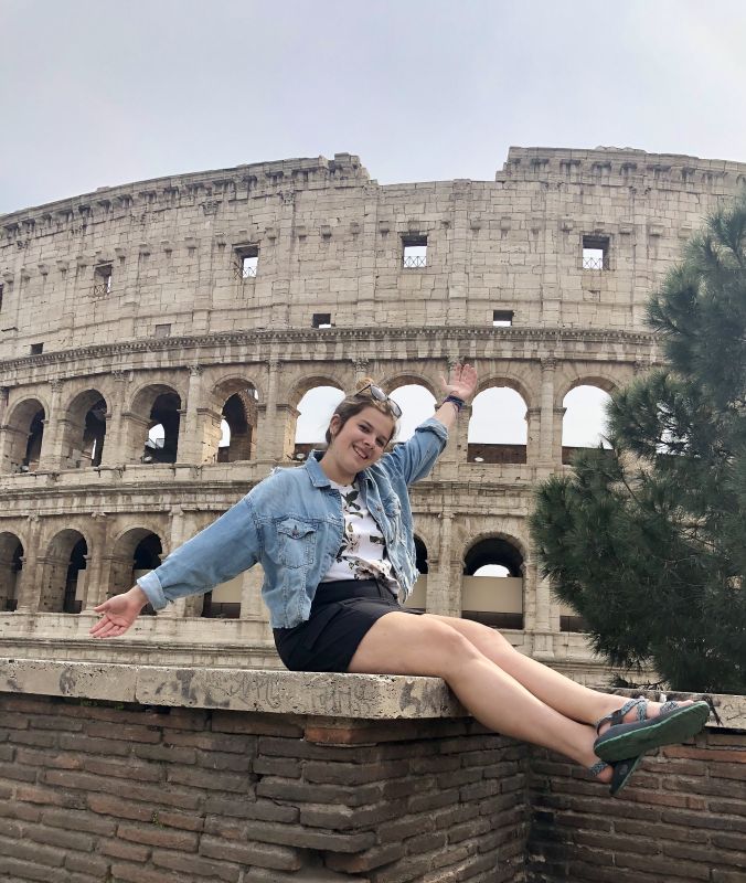 Female sitting in front of a Colosseum 