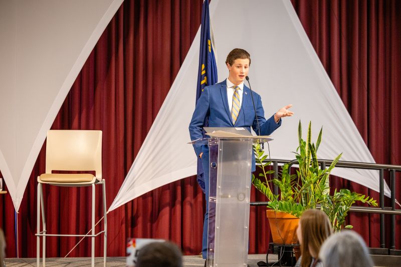A student standing up on stage speaking to other students