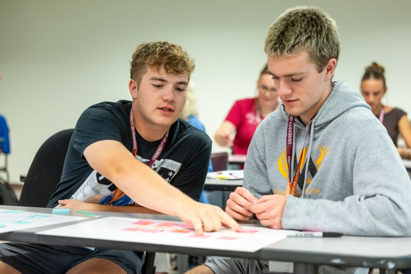 A student showing another student something on paper.