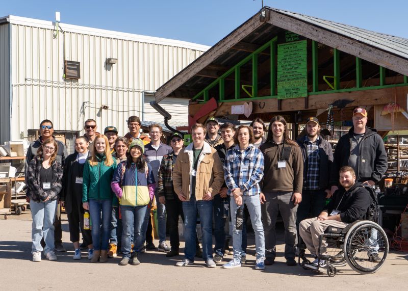 a large group of students poses outside a workshop as part of the ATG cognizant spring break