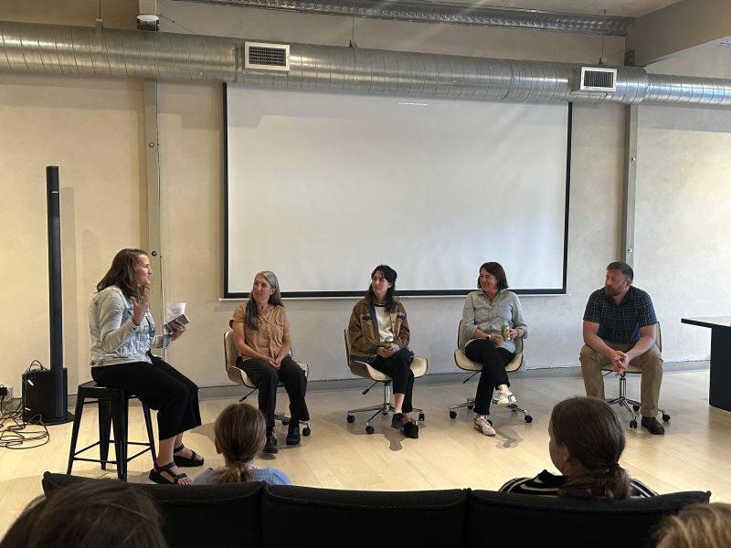 four professors participate in a panel discussion in front of a large projector screen