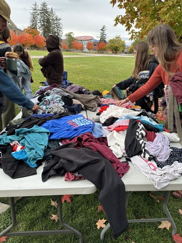 people sort through a giant pile of clothes at the clothing swap