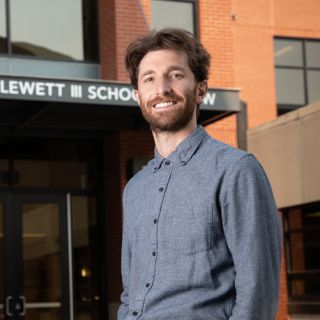 UM law student Noah Goldberg-Jaffe stands in front of the Alexander Blewett III School of Law building and smiles are the camera.