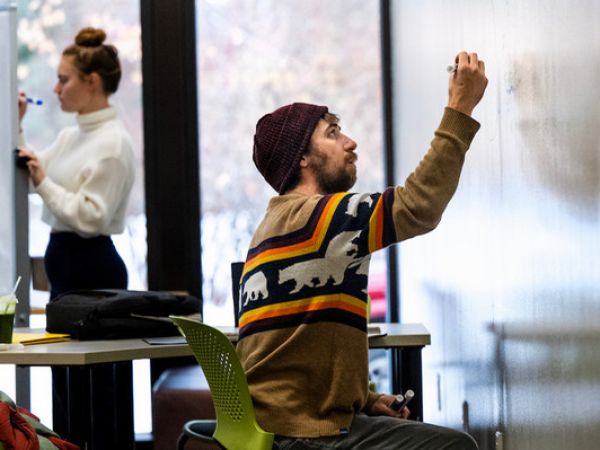 Two students work on whiteboards in the Mansfield Library