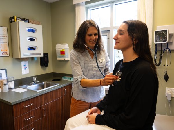 A student talks with a medical provider inside an exam room, seated across from each other during a consultation.