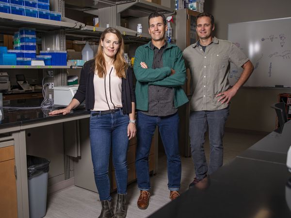 Three UM researchers stand in a lab