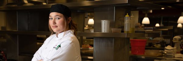 student chef with arms crossed standing in the Missoula College kitchen