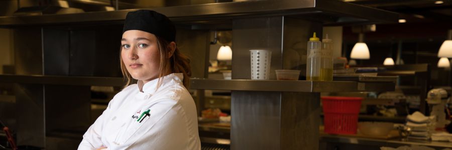 student chef with arms crossed standing in the Missoula College kitchen