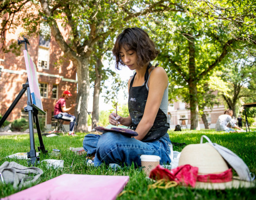 Woman painting at an outside easel. 